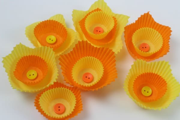 A number of yellow and orange cake cases layered to look like daffodil flowers with buttons in the center