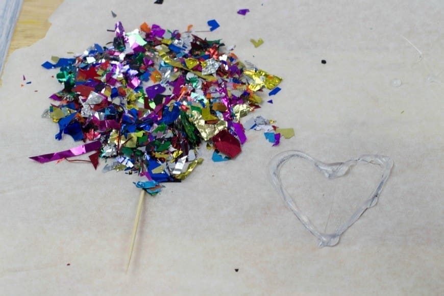 Hot Glue Gun Confetti Heart Cake Topper. This is a fab DIY craft to make a confetti heart, which is perfect as a cake topper for celebrations and if you only confetti one side they make a brilliant window cling. You could make any shape, letter, or number. You could even frame it as art instead of putting a toothpick in it as a cake topper