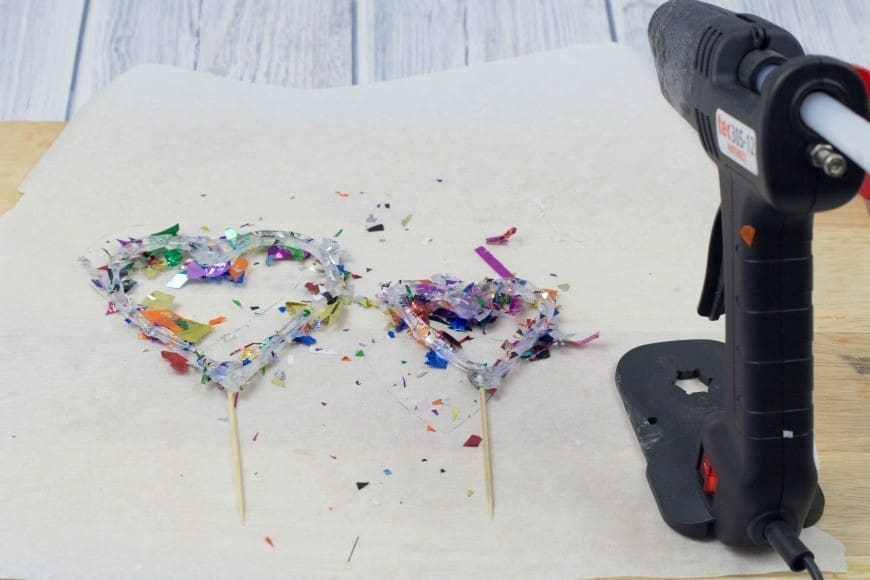 Hot Glue Gun Confetti Heart Cake Topper. This is a fab DIY craft to make a confetti heart, which is perfect as a cake topper for celebrations and if you only confetti one side they make a brilliant window cling. You could make any shape, letter, or number. You could even frame it as art instead of putting a toothpick in it as a cake topper