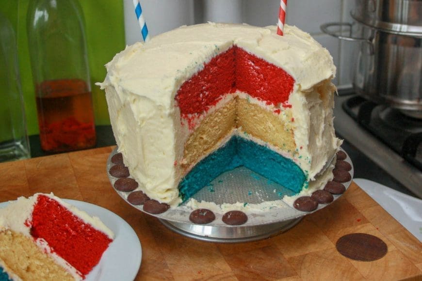 Red, white and blue layer cake with a white exterior and tiny union jack bunting hung on straws to celebrate the queens Jubilee