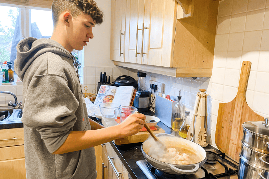 Teen in the kitchen cooking a King Prawn and Spicy Maple Curry