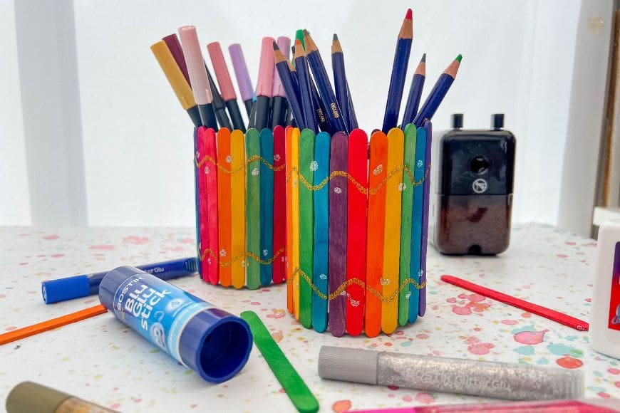 Two rainbow Popsicle Stick Pencil Cups one with pens in and one with pencils in