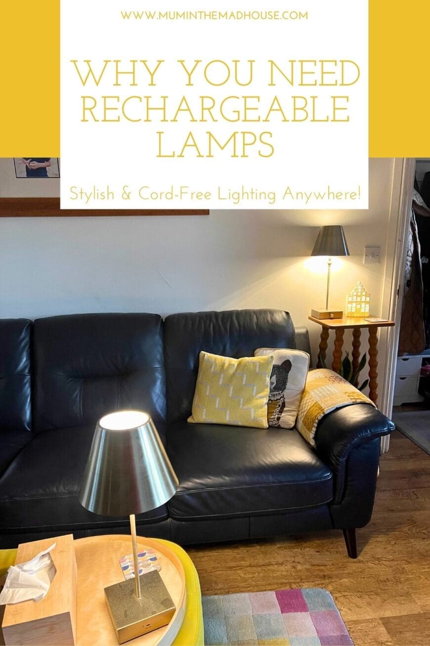 A modern brass rechargeable table lamp on a wooden tray in a living room, illuminating a black leather sofa with patterned yellow cushions. Another matching cordless lamp sits on a small wooden side table, adding warmth and ambiance. A cozy and stylish lighting solution without the hassle of cords