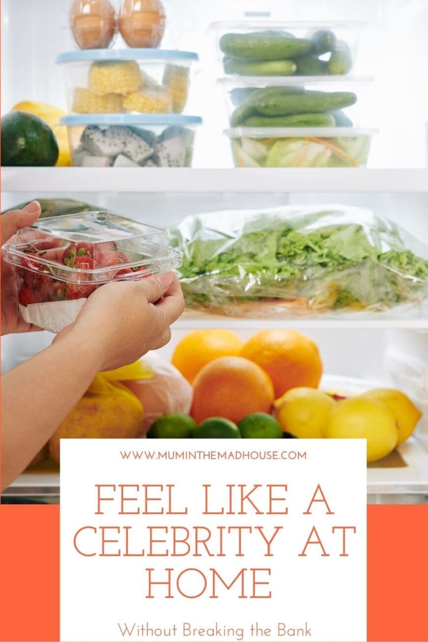 Hand placing a container of strawberries into a well-organized fridge filled with fresh produce, labeled wellness items, and neatly stacked containers – promoting a healthy, celebrity-inspired lifestyle.
